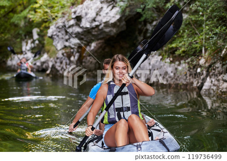 A group of friends enjoying having fun and kayaking while exploring the calm river, surrounding forest and large natural river canyons 119736499