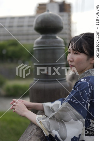 A young woman in a yukata standing on a bridge A young woman in a yukata standing on a bridge 119736848