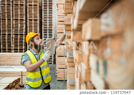 Worker Man with a bearded wearing safety uniform hard hat holding tablet working checking quality wooden at manufacturing wooden. Male carpenter worker wood warehouse industry. 119737047