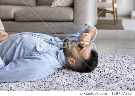 Tired depressed Hispanic man lying on home floor Tired depressed Hispanic man lying on home floor 119737132