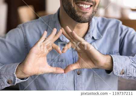 Cheerful young Caucasian man keeping hand heart gesture at chest Cheerful young Caucasian man keeping hand heart gesture at chest 119737211