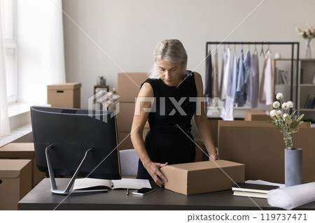 Older lady webstore worker prepare order for shipment at storehouse 119737471