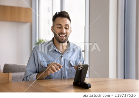 Happy Hispanic influencer man speaking at mobile phone web camera Happy Hispanic influencer man speaking at mobile phone web camera 119737520