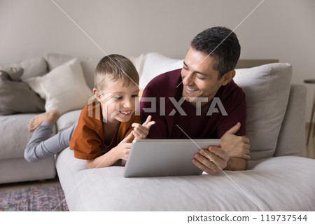 Cheerful dad and son kid using Internet technology at home Cheerful dad and son kid using Internet technology at home 119737544