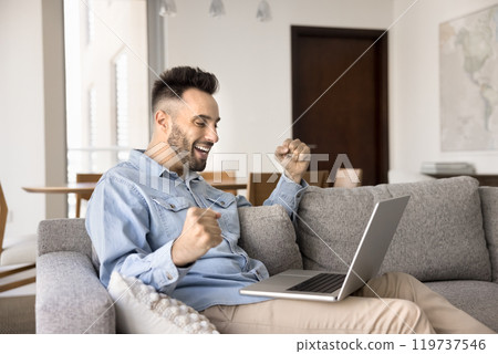 Cheerful excited young Hispanic business man making winner yes hands 119737546