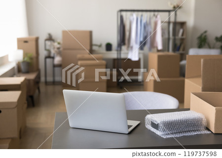 Laptop on table with belongings in boxes at new store Laptop on table with belongings in boxes at new store 119737598