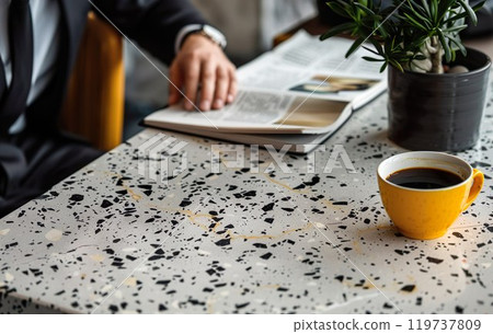 Successful businessman entrepreneur in a black business suit in cafe reading newspaper. A yellow cup of espresso coffee on stone modern table. This is AI-generated item 119737809