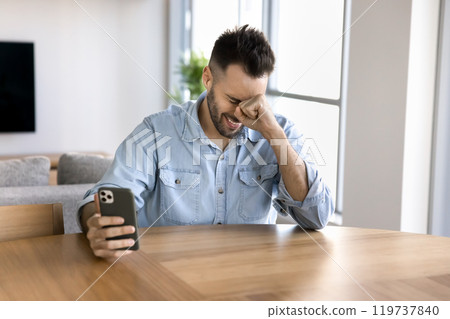 Cheerful young Latin man using mobile phone and laughing Cheerful young Latin man using mobile phone and laughing 119737840