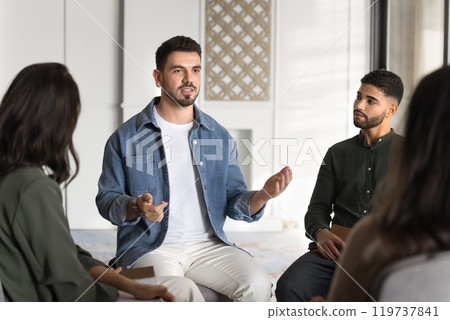 Serious male Middle Eastern group therapy patient talking to community Serious male Middle Eastern group therapy patient talking to community 119737841