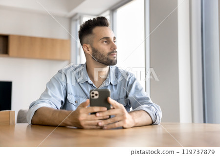 Pensive serious Hispanic freelance business man holding smartphone 119737879