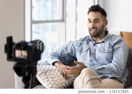 Positive Latin blogger man filming video on reflex camera Positive Latin blogger man filming video on reflex camera 119737885