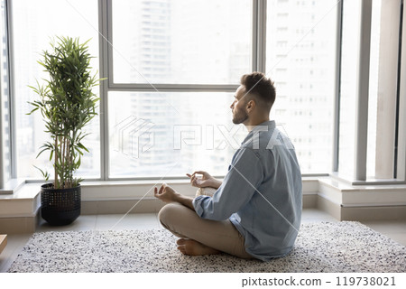 Peaceful focused young Latin yogi man meditating at home Peaceful focused young Latin yogi man meditating at home 119738021