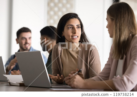 Confident Hispanic businesswoman in casual talking to female colleague 119738214