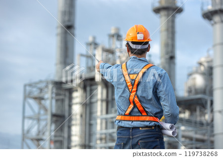 Asian worker power plant factory holding blueprint pointing check construction plan power plant. Engineer wearing safety uniform helmet at energy petrochemical industry. 119738268