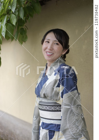 A young woman in a yukata standing against a wall 119738482