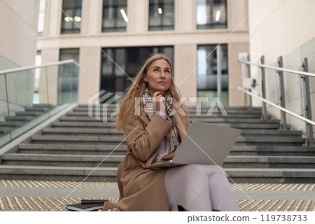 A thoughtful businesswoman working on her laptop at a business center during a sunny afternoon 119738733