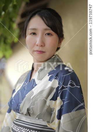 A young woman in a yukata standing against a wall 119738747