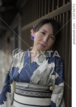 A young woman in a yukata standing at a lattice door A young woman in a yukata standing at a lattice door 119738751