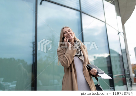 A businesswoman walks near a business center while talking on her phone 119738794
