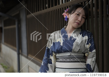 一位穿著浴衣的年輕女子站在格子門旁 119739018