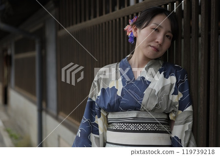 A young woman in a yukata standing at a lattice door A young woman in a yukata standing at a lattice door 119739218