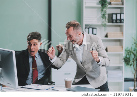 Two happy colleagues with laptop and documents in office Two happy colleagues with laptop and documents in office 119739313