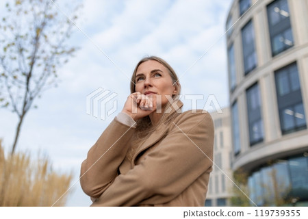 A businesswoman pauses thoughtfully outside a modern business center, considering her next steps 119739355