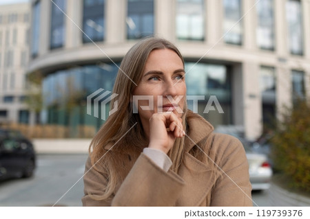 A businesswoman stands outside a modern business center, contemplating the day ahead 119739376