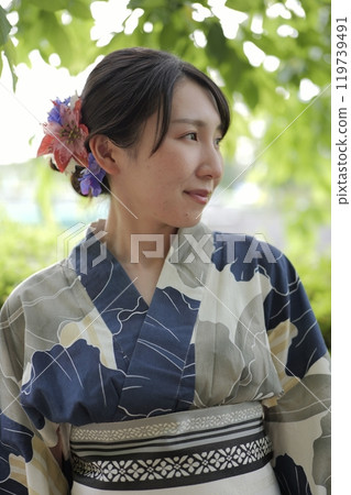 A young woman in a yukata standing in green leaves A young woman in a yukata standing in green leaves 119739491