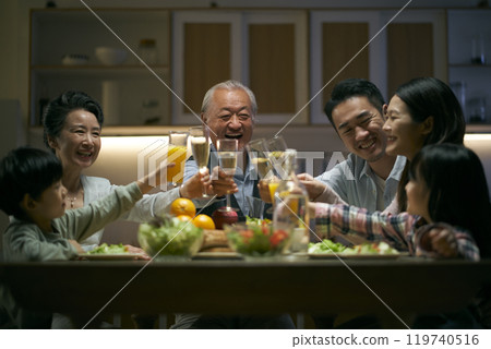 three generation asian family toasting while having dinner together 119740516
