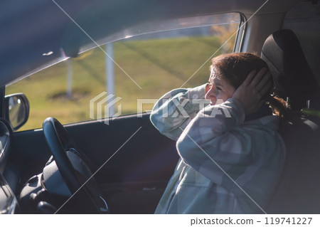 Caucasian woman holds hands on head while driving in panic. Caucasian woman holds hands on head while driving in panic. 119741227