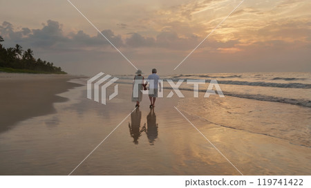elderly couple walking at the beach elderly couple walking at the beach 119741422
