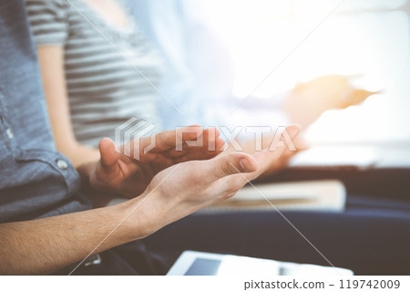 Business people clapping at meeting or conference, close-up of hands. Group of unknown businessmen and women in sunny office 119742009