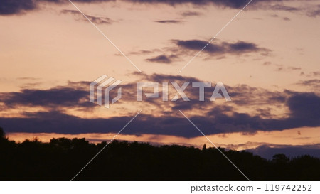 See a picturesque sunset where deep red colors mingle with dark clouds. The peaceful atmosphere adds to the beauty of this peaceful landscape. 119742252
