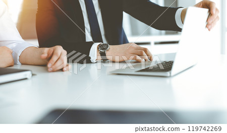 Unknown business people using laptop computer at the desk in modern office. Businessman or male entrepreneur is working with his colleague. Teamwork and partnership concept Unknown business people using laptop computer at the desk in modern office. Businessman or male entrepreneur is working with his colleague. Teamwork and partnership concept 119742269