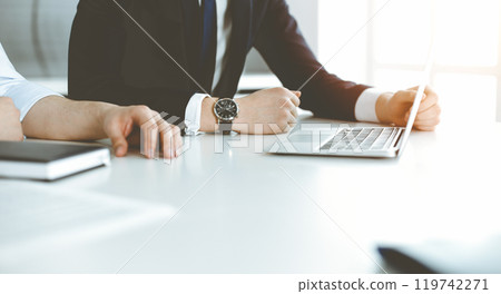 Unknown business people using laptop computer at the desk in modern office. Businessman or male entrepreneur is working with his colleague. Teamwork and partnership concept Unknown business people using laptop computer at the desk in modern office. Businessman or male entrepreneur is working with his colleague. Teamwork and partnership concept 119742271