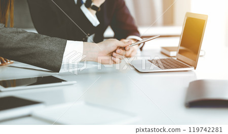 Unknown businessmen and woman sitting, using laptop computer and discussing questions at meeting in sunny office, close-up. Success concept 119742281