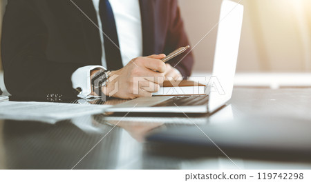 Unknown businessmen and woman sitting, working and discussing questions at meeting in sunny office, close-up. Success concept Unknown businessmen and woman sitting, working and discussing questions at meeting in sunny office, close-up. Success concept 119742298