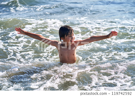 An 11 year old boy in having fun in the sea waves. 119742592