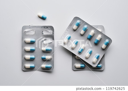 Packs of white and blue capsules of medical preparations on a white background. Packs of white and blue capsules of medical preparations on a white background. 119742625