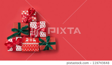 Alternative Christmas tree of holiday gifts on red background. Boxing day. Greeting card. Happy New Year. View from above, flat lay. Template, mockup. Alternative Christmas tree of holiday gifts on red background. Boxing day. Greeting card. Happy New Year. View from above, flat lay. Template, mockup. 119743648