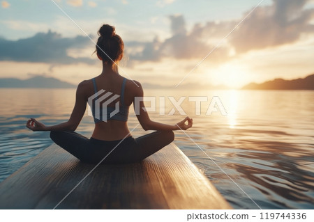Young woman practicing yoga at sunset on sup board on a lake Young woman practicing yoga at sunset on sup board on a lake 119744336
