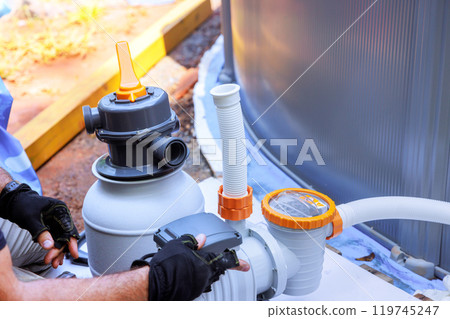 Maintenance workers assemble sand filter system tank, as well as equipment for cleaning swimming pools 119745247
