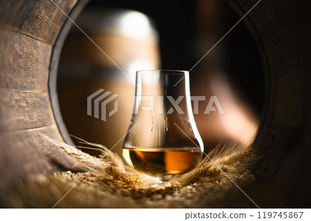 A glass of bourbon Whiskey in oak barrel 119745867