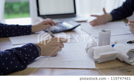 Accountants or auditors reviewing financial documents while usin Accountants or auditors reviewing financial documents while usin 119747481