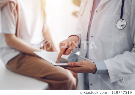 Doctor and patient in clinic. Friendly physician using tablet computer near a young woman. Medicine concept 119747519