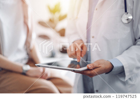 Doctor and patient in clinic. Friendly physician using tablet computer near a young woman. Medicine concept Doctor and patient in clinic. Friendly physician using tablet computer near a young woman. Medicine concept 119747525