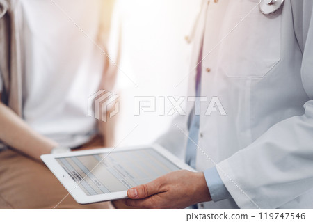 Doctor and patient discussing perfect health exam results. Friendly physician keeping tablet computer with her hands near a young woman. Medicine concept Doctor and patient discussing perfect health exam results. Friendly physician keeping tablet computer with her hands near a young woman. Medicine concept 119747546