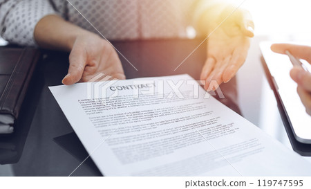 Business people sitting and discussing contract in office, closeup. Partners or lawyers working together at meeting before signing papers. Teamwork and partnership Business people sitting and discussing contract in office, closeup. Partners or lawyers working together at meeting before signing papers. Teamwork and partnership 119747595