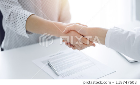 Business people shaking hands above contract papers just signed on the white table, closeup. Lawyers at meeting. Teamwork, partnership, success concept 119747608